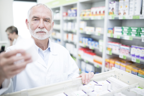 Pharmacist taking medicine from cabinet in pharmacy stock photo