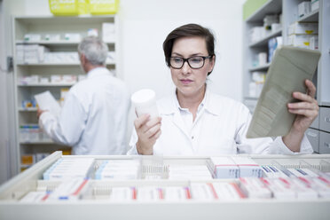 Pharmacist with tablet and medicine at cabinet in pharmacy - WESTF23996