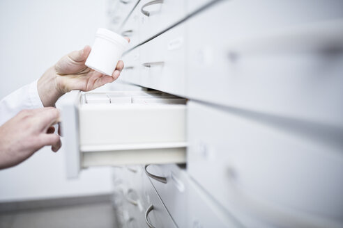 Nahaufnahme eines Apothekers, der Medikamente aus einem Schrank in einer Apotheke nimmt - WESTF23999