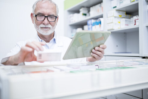 Apothekerin mit Tablet und Medikament am Schrank in der Apotheke - WESTF24002