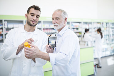 Zwei Pharmazeuten, die in der Apotheke Medikamente untersuchen - WESTF24003