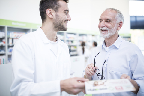 Pharmacist smiling at mature man in pharmacy stock photo
