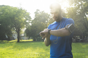 Runner in urban park checking his smartwatch - SBOF01110