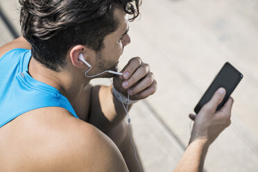 Läufer mit Kopfhörern, der Nachrichten auf seinem Smartphone abruft - SBOF01173