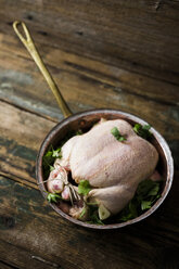 Uncooked chicken with parsley and potatoes in a saucepan - GIOF03733