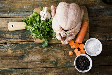 Rohes Hühnerfleisch mit Karotten, Petersilie, Knoblauch, Pfeffer und Salz auf einem Schneidebrett - GIOF03736