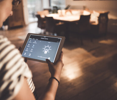 Woman using tablet with smart home control functions at home - UUF12500