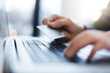 Man using laptop and holding credit card, close-up - DIGF03218