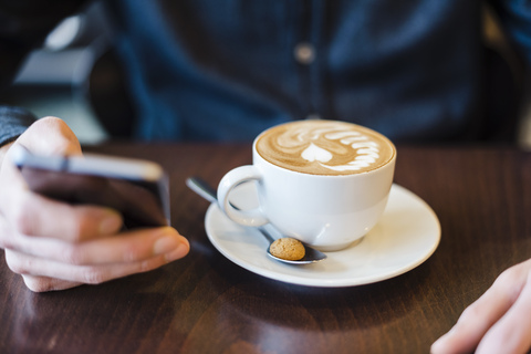 Man using cell phone in a coffee shop, close-up stock photo