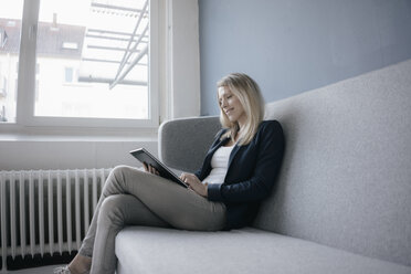 Smling Geschäftsfrau sitzt auf der Couch mit Tablet - JOSF02090