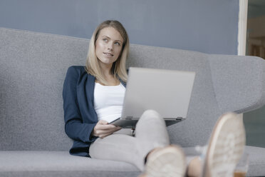 Porträt einer nachdenklichen Geschäftsfrau, die mit einem Laptop auf einer Couch sitzt - JOSF02097