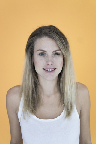 Porträt einer lächelnden Frau vor einem gelben Hintergrund, lizenzfreies Stockfoto