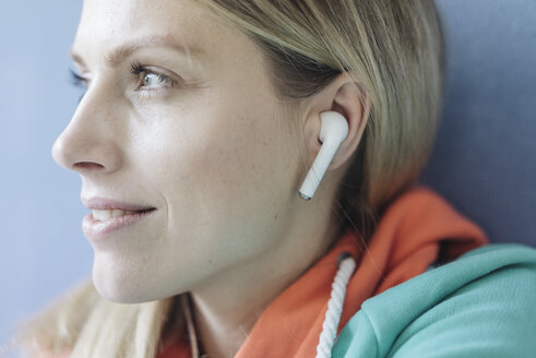 Porträt einer lächelnden Frau, die mit drahtlosen Kopfhörern Musik hört, Nahaufnahme - JOSF02111