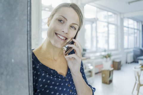 Portrait of happy young woman on the phone in a loft stock photo