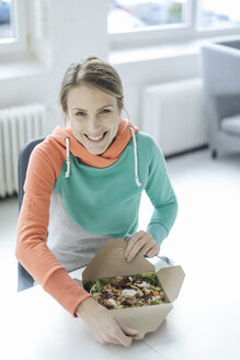 Porträt einer lachenden jungen Frau beim Mittagessen im Büro - JOSF02145