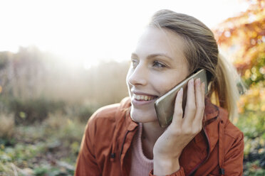 Porträt einer jungen Frau beim Telefonieren in einem herbstlichen Park - JOSF02148