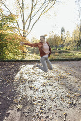 Happy young woman jumping in the air in autumnal park - JOSF02150
