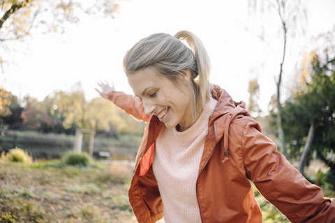 Porträt einer glücklichen jungen Frau, die in einem herbstlichen Park balanciert, lizenzfreies Stockfoto