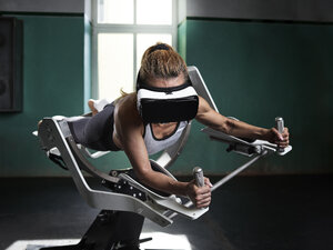 Woman wearing VR glasses using futuristic fitness machine - CVF00014