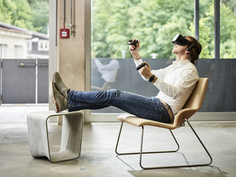 Man wearing VR glasses sitting on chair stock photo