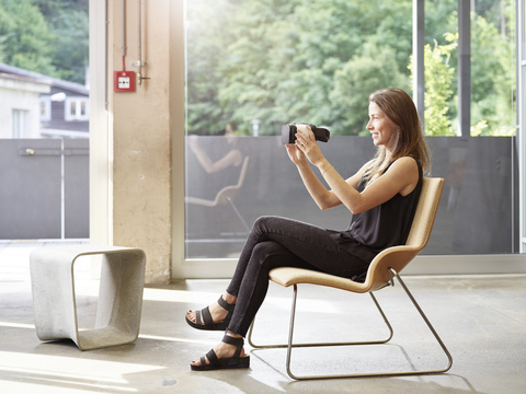 Frau mit VR-Brille auf einem Stuhl sitzend, lizenzfreies Stockfoto