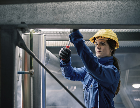 Handwerkerin mit Schutzhelm bei der Arbeit, lizenzfreies Stockfoto