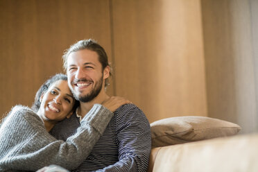 Porträt eines glücklichen jungen Paares auf der Couch sitzend - FMKF04682