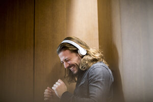Porträt eines aufgeregten Mannes, der mit Kopfhörern Musik hört - FMKF04688