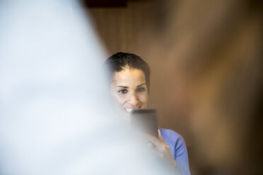 Portrait of laughing woman taking photo with cell phone - FMKF04699