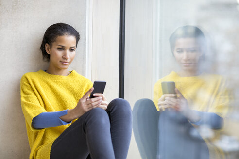 Porträt einer jungen Frau, die ein Mobiltelefon benutzt - FMKF04706