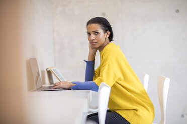 Porträt einer jungen Frau mit gelbem Pullover und Laptop - FMKF04709