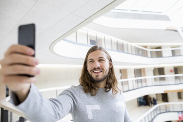 Porträt eines lächelnden Mannes, der ein Selfie mit seinem Handy macht - FMKF04732