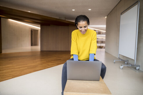 Lachende junge Frau mit Laptop in der Universität - FMKF04734