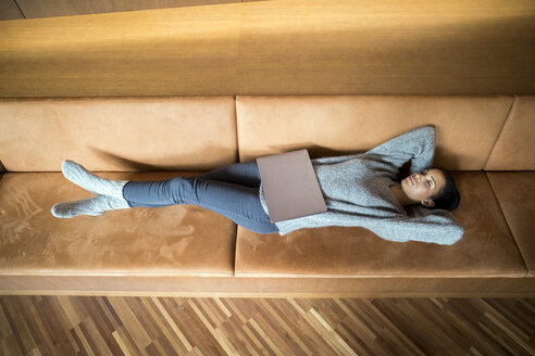 Frau mit Laptop entspannt auf Couch - FMKF04739