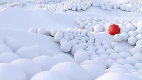 Red ball among big group of white spheres stock photo