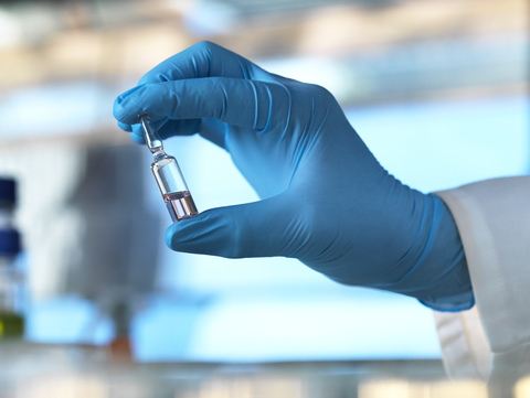 Wissenschaftler, der ein Fläschchen mit einer Flüssigkeit im Labor hält, lizenzfreies Stockfoto