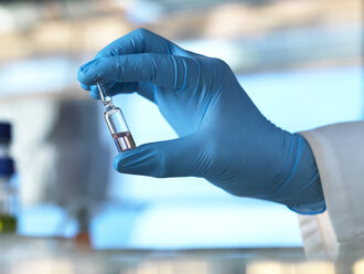 Wissenschaftler, der ein Fläschchen mit einer Flüssigkeit im Labor hält - ABRF00020