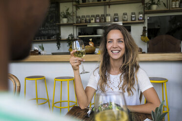 Lächelnde Frau mit einem Glas Wein, die einen Mann in einem Café ansieht - SBOF01177