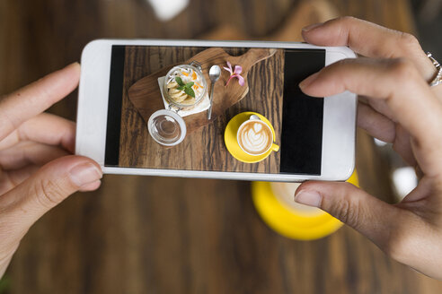 Weibliche Hände, die ein Foto von Müsli und Kaffee mit einem Smartphone machen - SBOF01181