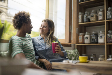 Smiling couple sitting in cozy cafe in front of window - SBOF01191