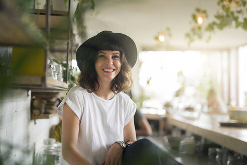 Porträt einer Frau mit schwarzem Hut hinter der Theke eines Cafés - SBOF01208