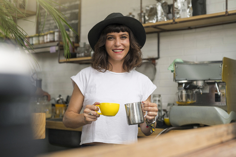 Porträt einer Frau mit schwarzem Hut hinter der Theke, die einen Kaffee zubereitet, lizenzfreies Stockfoto