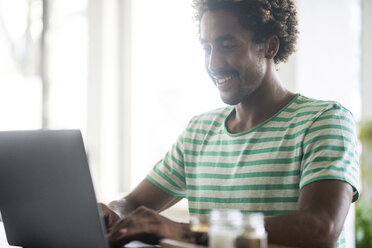 Smiling man using laptop in a cafe - SBOF01222