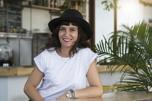 Porträt einer Frau mit schwarzem Hut hinter der Theke eines Cafés - SBOF01237