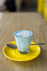 Blauer Schlumpf-Latte mit Spirulina im Glas auf gelber Untertasse - SBOF01242