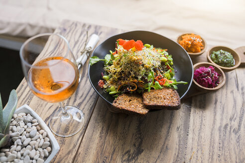 Dekorierte Salatschüssel auf Holztisch mit Glas Rosenwein - SBOF01249