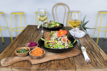 Dekorierte Salatschüsseln auf Holztisch mit Weingläsern - SBOF01250