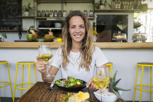 Portrait of smiling woman holding glass of wine in a cafe - SBOF01251