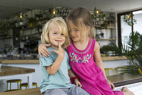 Porträt einer Schwester, die ihren Bruder in einem Café umarmt - SBOF01254