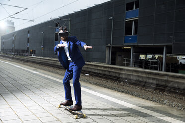 Young man with longboarding at train station, using VR glasses - MAEF12506